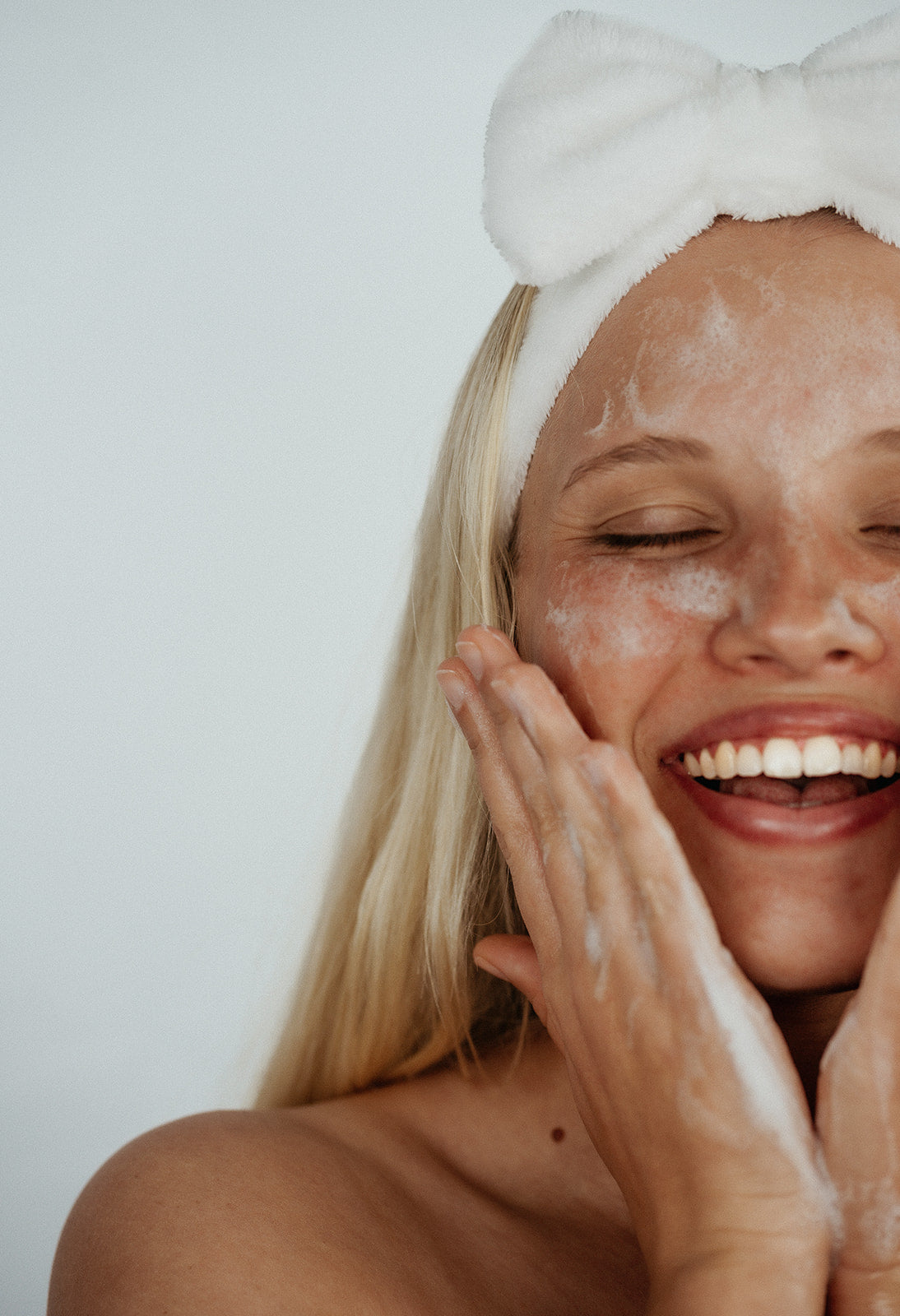 fluffy white ks kindred skincare headband to use for skincare routine to wash face with and keep hair back blonde girl wearing it whilst washing her face with all skin types deep sea gel cleanser