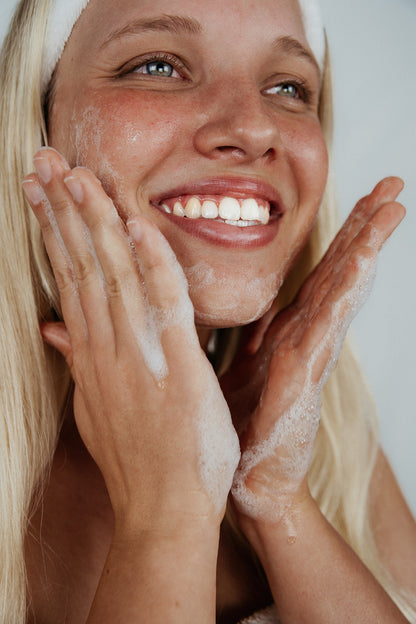 blonde girl with acne free no pimples putting kindred skincare deep sea gel cleanser on her face washing away bacteria