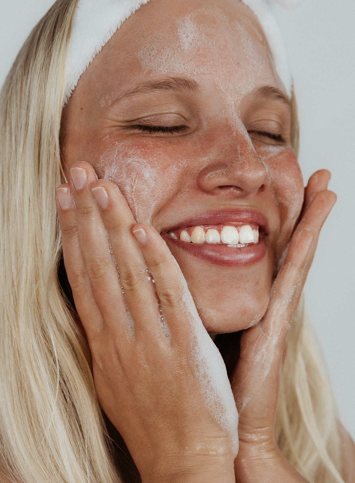 blonde girl with acne free no pimples putting kindred skincare deep sea gel cleanser on her face washing away bacteria